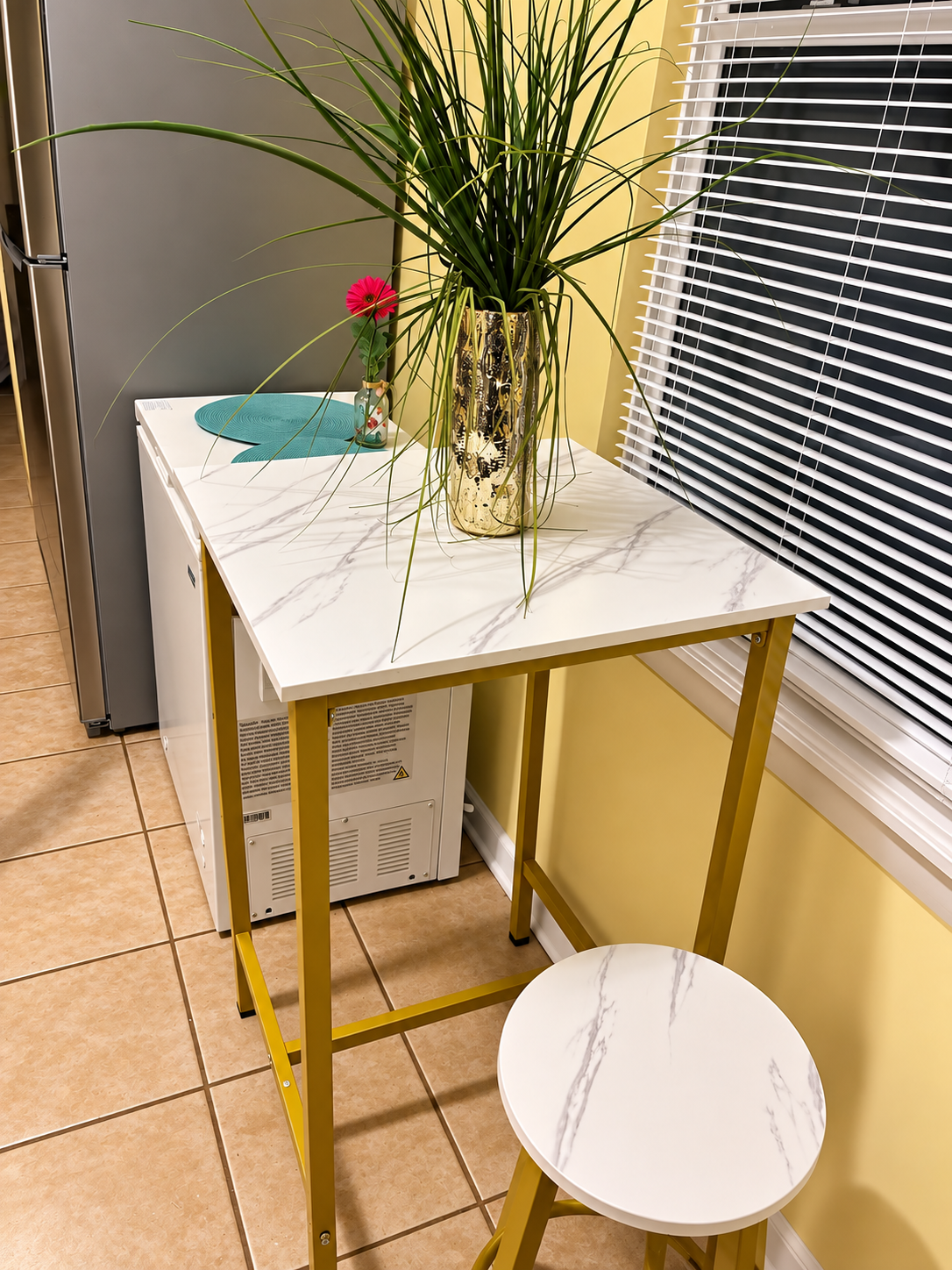 Kitchen nook — white table with gold legs, decorative plant, and window light