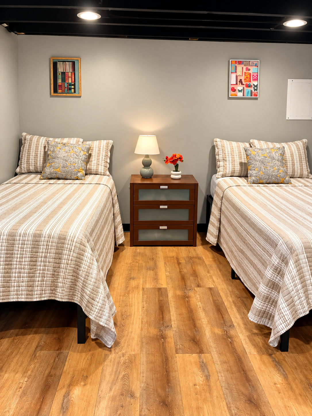 Second bedroom — two twin beds, colorful wall art, warm wood floors